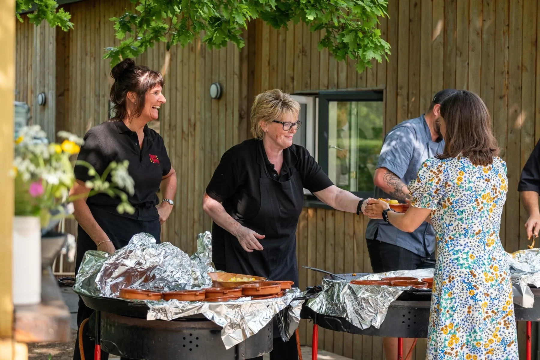 Buen Apetito team serving guests around a live-cooking paella pan at a wedding